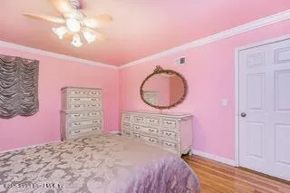 a bedroom with a bed a dresser and potted plants