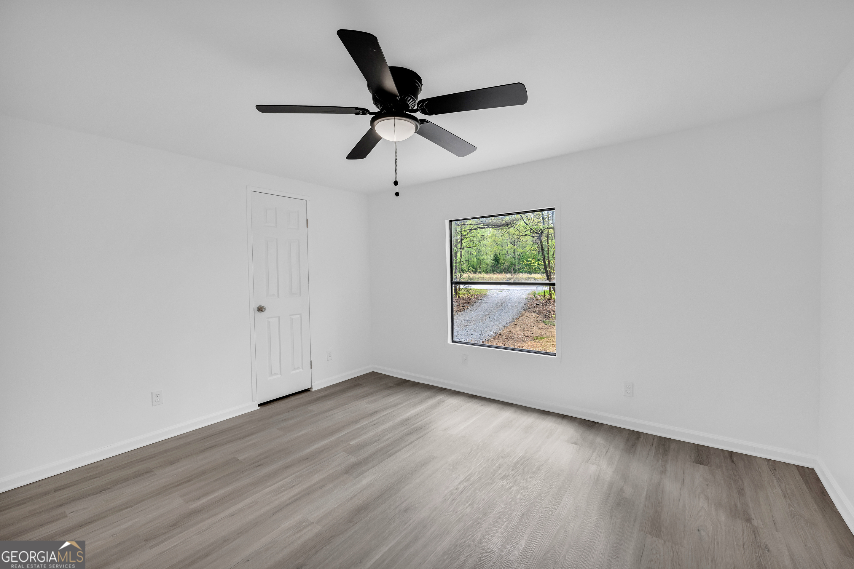 1144 Wolfskin Road Arnoldsville, GA 30619 - Photo 25 of 41 an empty room with wooden floor a ceiling fan and windows