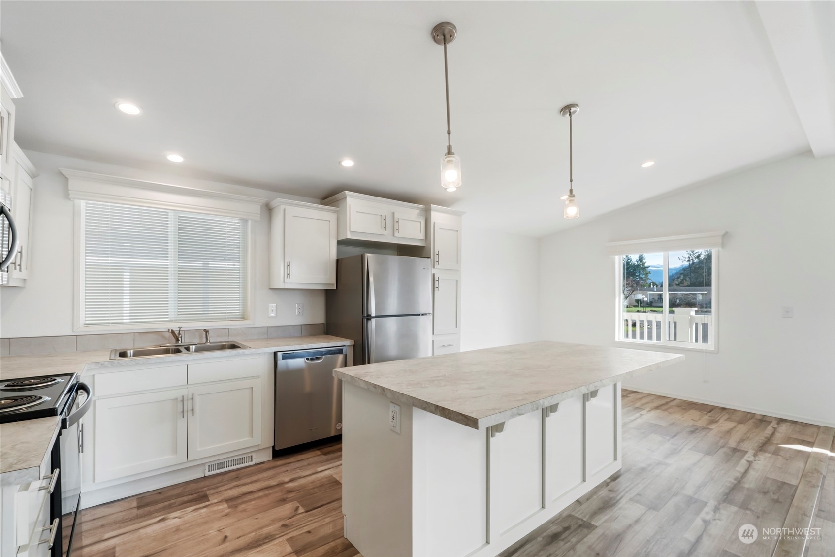 943 Pine Drive Enumclaw, WA 98022 - Photo 8 of 21 a kitchen with a sink a stove a refrigerator and island with wooden floor