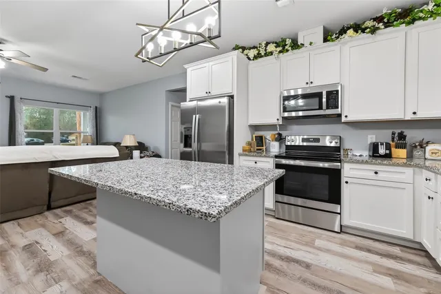 a kitchen with granite countertop a sink stainless steel appliances and white cabinets