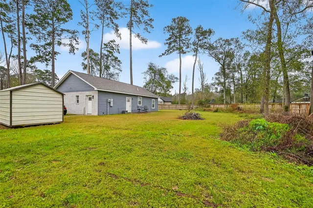 a view of a house with a yard and a large tree