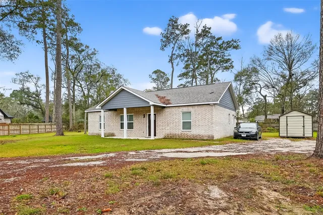 a view of a house with a yard and large trees
