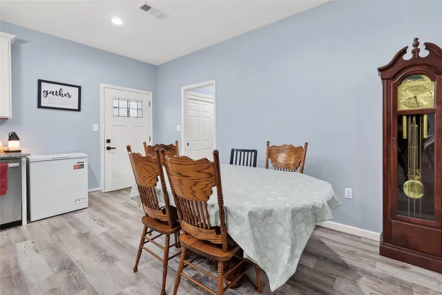 a open kitchen with stainless steel appliances granite countertop a stove top oven a refrigerator a dining table and chairs with wooden floor