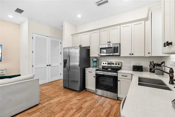 a kitchen with stainless steel appliances granite countertop a refrigerator stove and sink with wooden floor