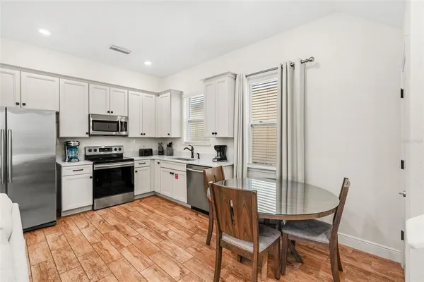 a kitchen with granite countertop stainless steel appliances a refrigerator a stove a dining table and chairs