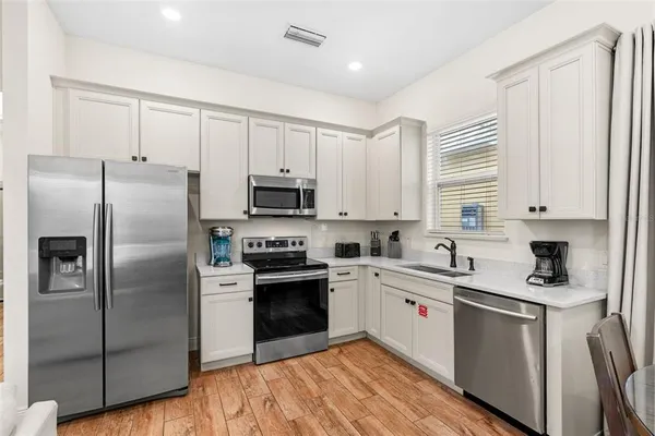 a kitchen with white cabinets stainless steel appliances and a window