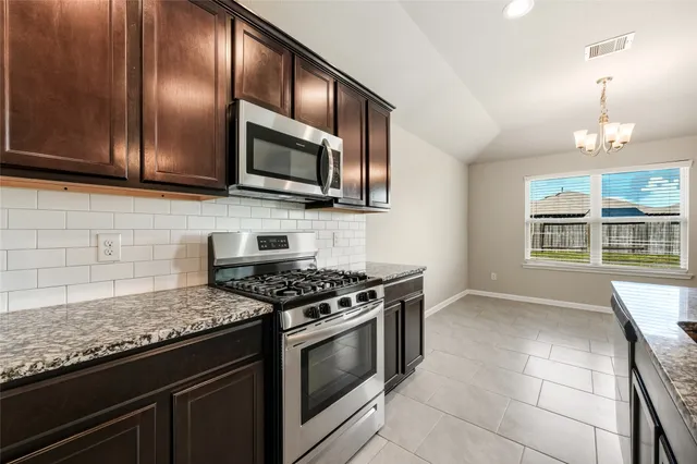 a kitchen with stainless steel appliances granite countertop wooden cabinets a stove top oven a sink and dishwasher