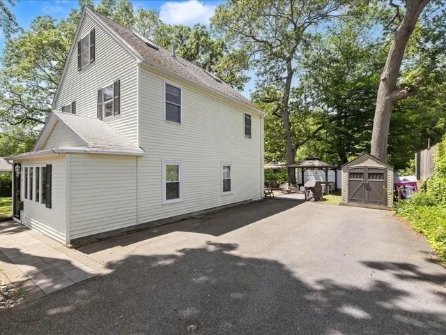 a view of a white house with a large space and large trees