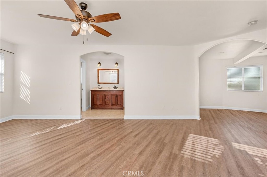 3271 East Muscat Avenue Fresno, CA 93725 - Photo 29 of 53 an empty room with wooden floor chandelier fan and windows