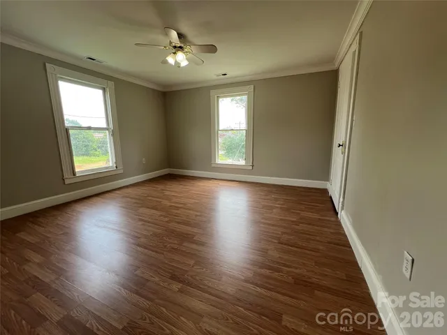 an empty room with wooden floor and windows