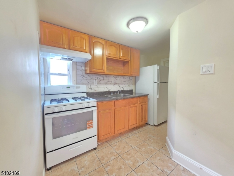 27 Geneva Street Elizabeth Port, NJ 07206 - Photo 5 of 12 a kitchen with a stove a sink and a refrigerator