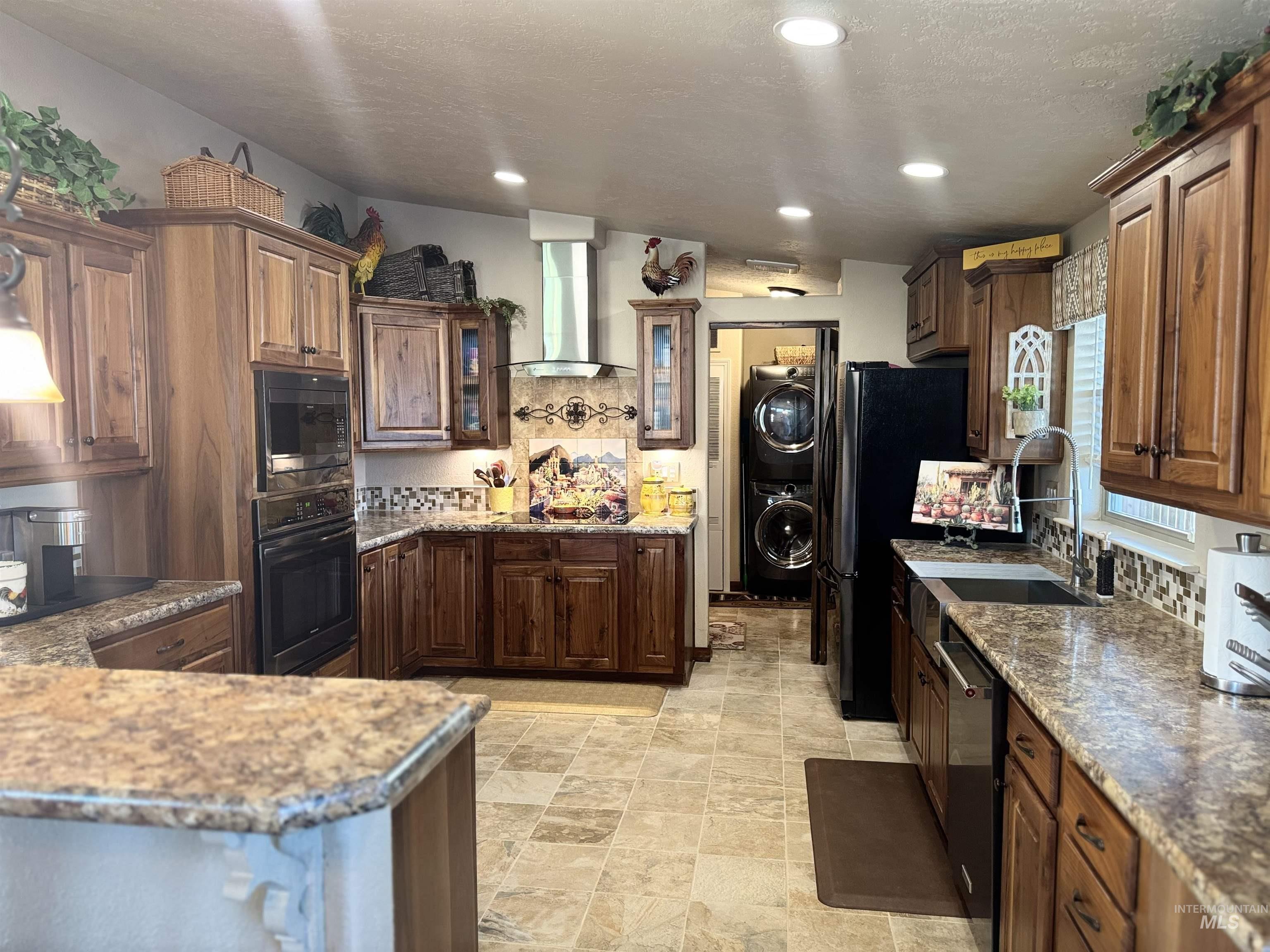 811 14th Street Clarkston, WA 99403 - Photo 18 of 50 Kitchen featuring backsplash, glass insert cabinets, black appliances, wall chimney range hood, and dark stone counters