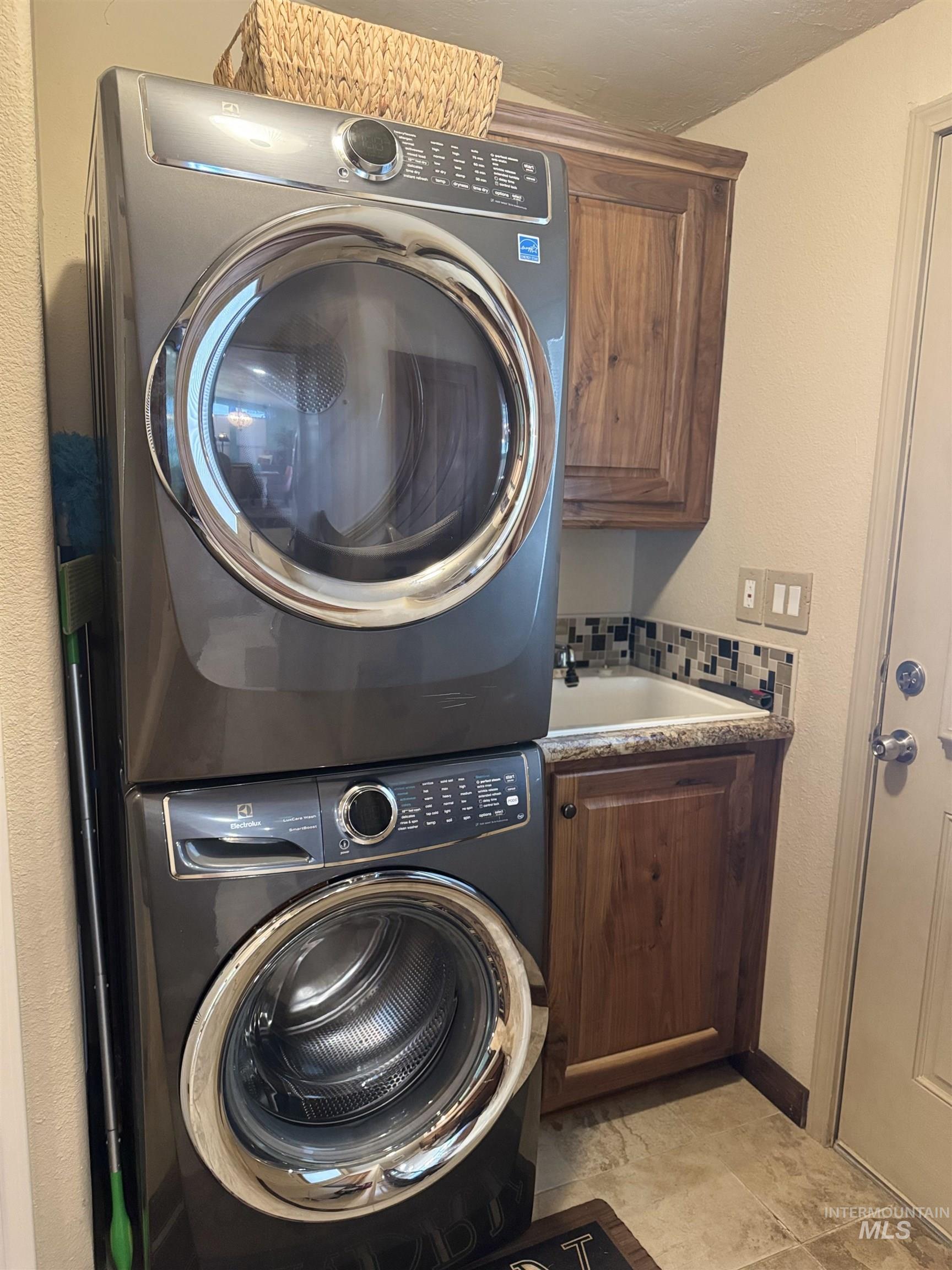 811 14th Street Clarkston, WA 99403 - Photo 31 of 50 Laundry room with a textured wall, stacked washing machine and dryer, and cabinet space