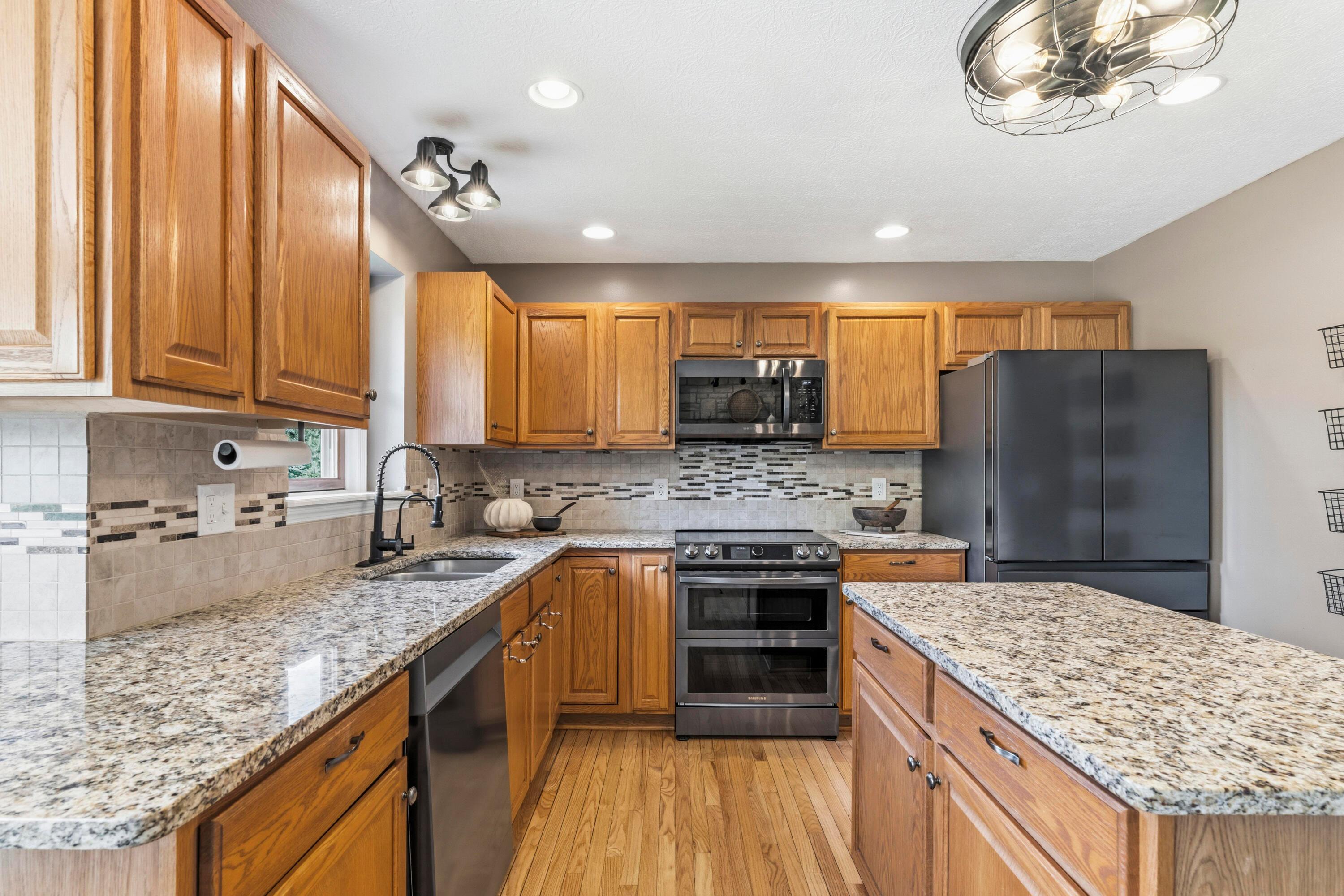 8507 Benner Road Johnstown, OH 43031 - Photo 21 of 69 Large Kitchen with hardwood floors and Dining Area with bay window & double fireplace! Granite countertops, island, NEW Black Stainless Steel Appliances, including an induction oven! NEW Reverse Osmosis to sink/Fridge/Brio+