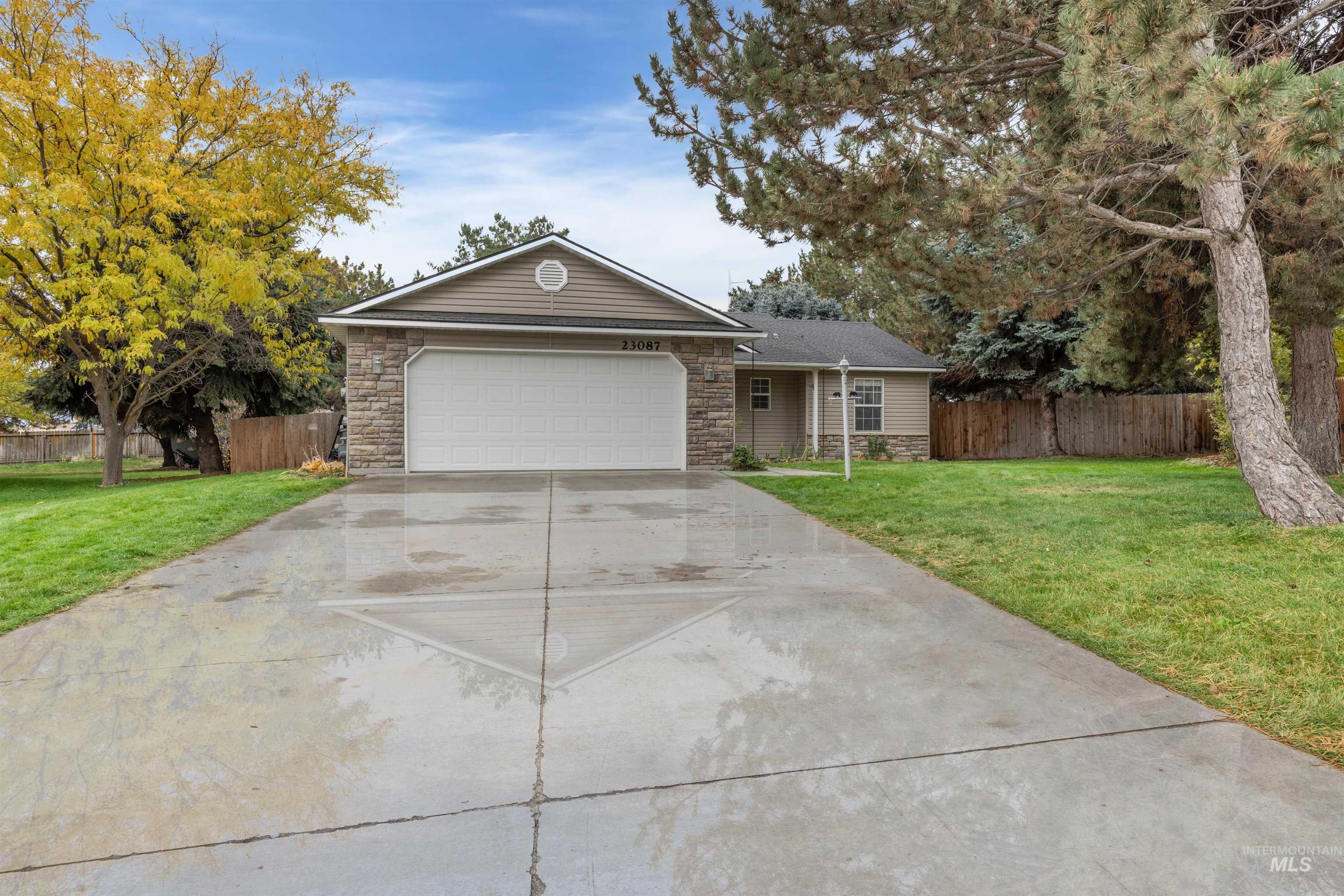 23087 Forest Hills Loop Caldwell, ID 83607 - Photo 1 of 1 Ranch-style house with driveway, stone siding, and a garage