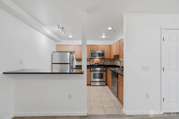 a kitchen with stainless steel appliances kitchen island granite countertop a refrigerator and a stove top oven