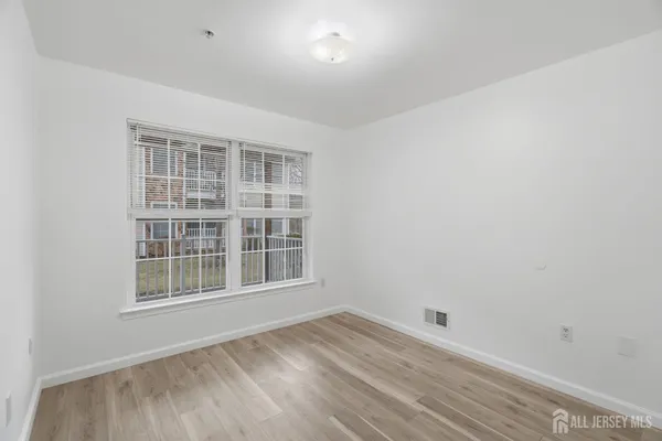 a view of empty room with wooden floor and windows
