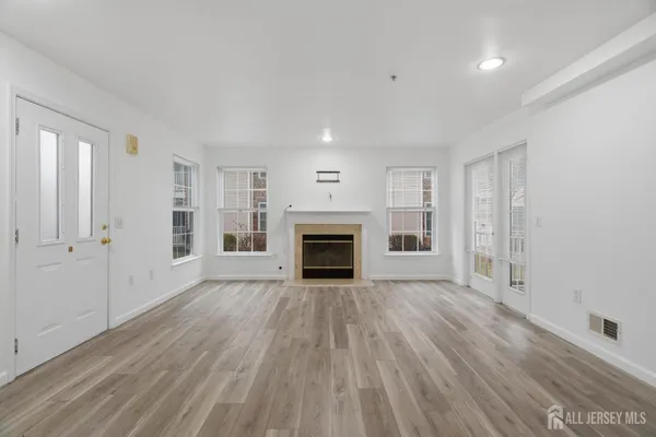 an empty room with wooden floor fireplace and windows