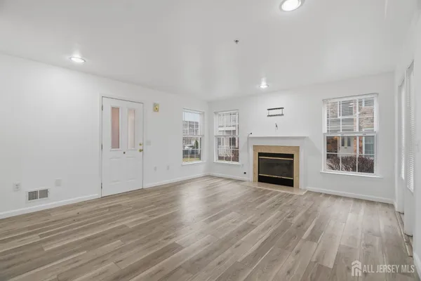 an empty room with wooden floor fireplace and windows