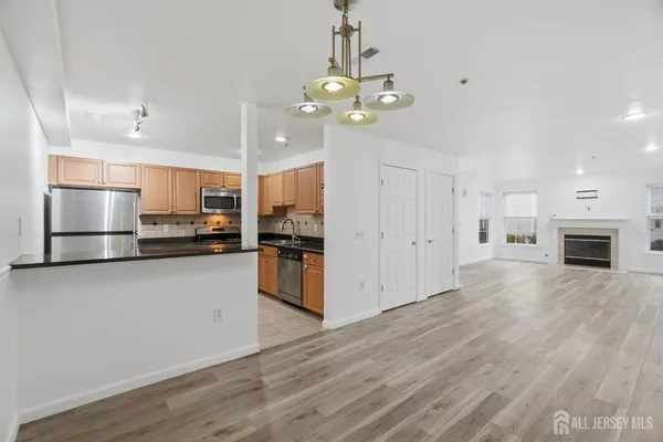 a kitchen with stainless steel appliances granite countertop a refrigerator a sink dishwasher a oven and a dining table with wooden floor
