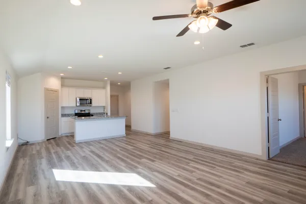 a large kitchen with kitchen island a sink dishwasher a stove and a refrigerator with wooden floor