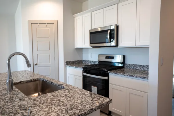 a kitchen with granite countertop a sink and a stove top oven