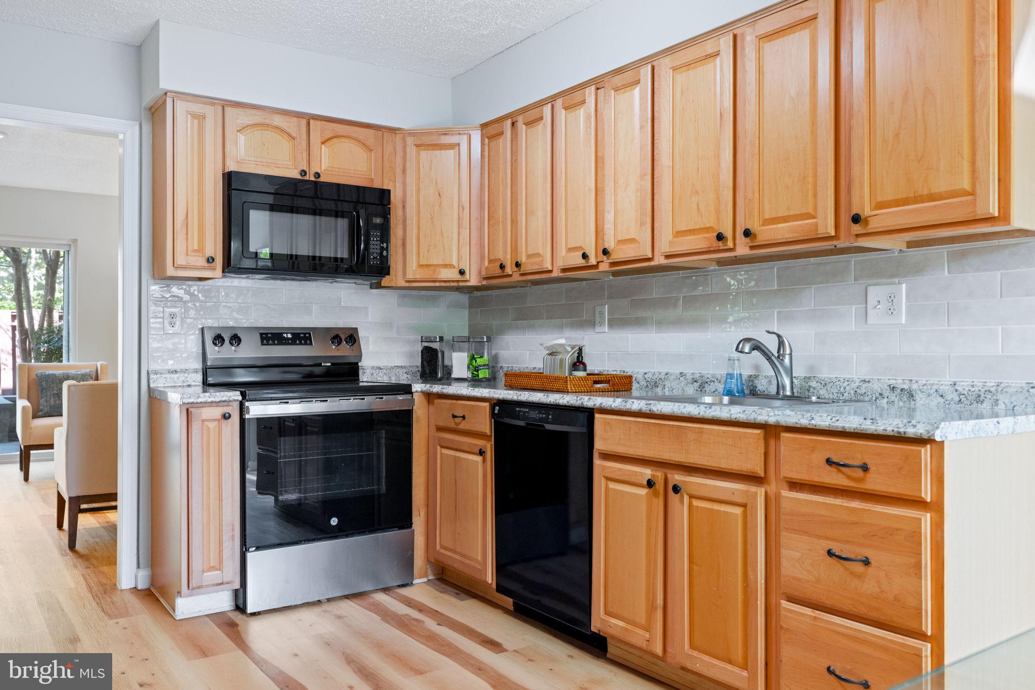 2389 Southgate Square Reston, VA 20191 - Photo 12 of 56 a kitchen with stainless steel appliances granite countertop a stove a sink and a microwave