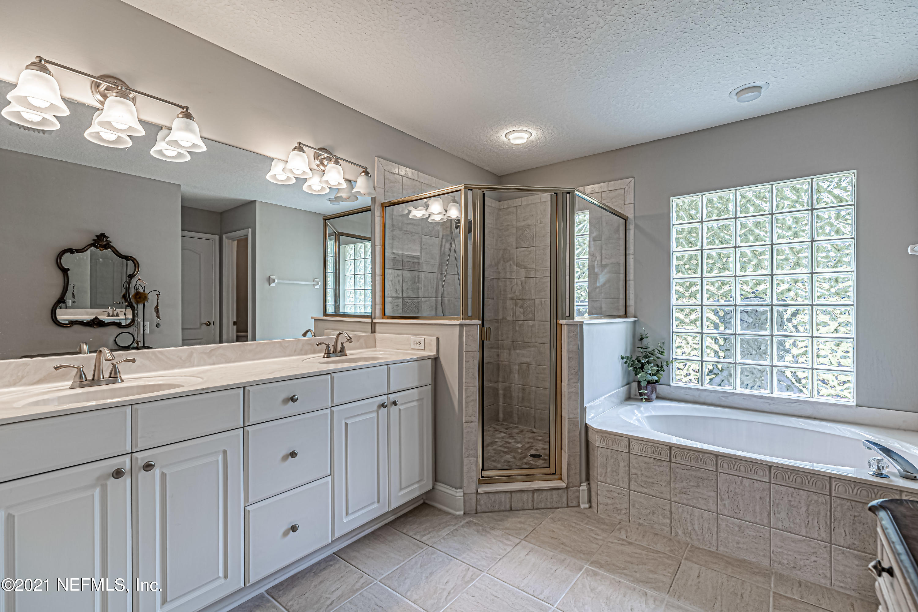 184 Circuit Rider Road Green Cove Springs, FL 32043 - Photo 32 of 58 a spacious bathroom with a double vanity sink a large mirror and a bathtub with shower