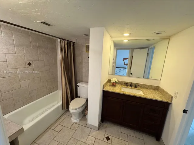 a bathroom with a granite countertop sink a toilet and a bathtub
