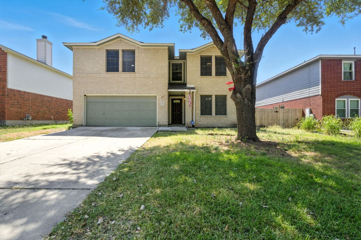 Traditional-style house featuring brick siding, a garage, and concrete driveway