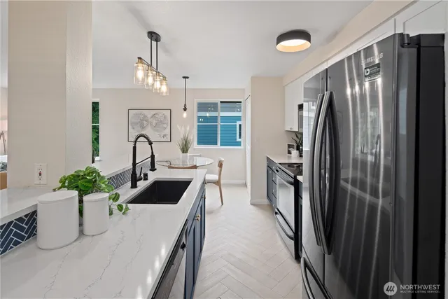 a kitchen with stainless steel appliances a sink a stove a refrigerator cabinets and a dining table