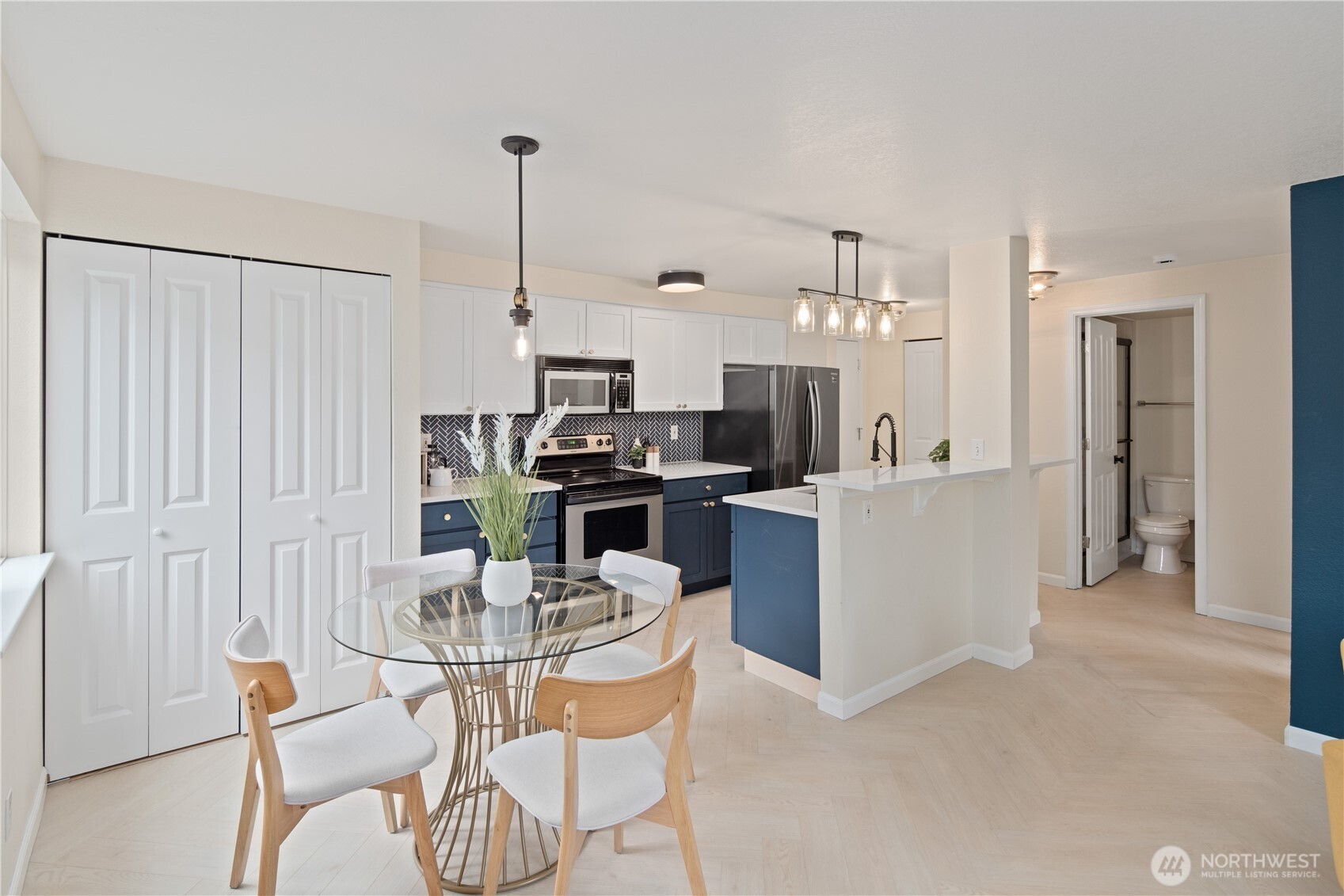 300 10th Avenue, Unit A302 Seattle, WA 98122 - Photo 8 of 27 a kitchen with stainless steel appliances kitchen island granite countertop a table and chairs in it