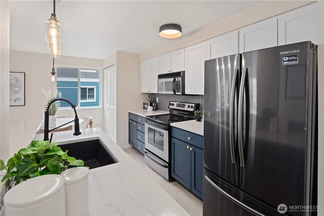 a kitchen with stainless steel appliances kitchen island granite countertop a refrigerator a stove and a sink
