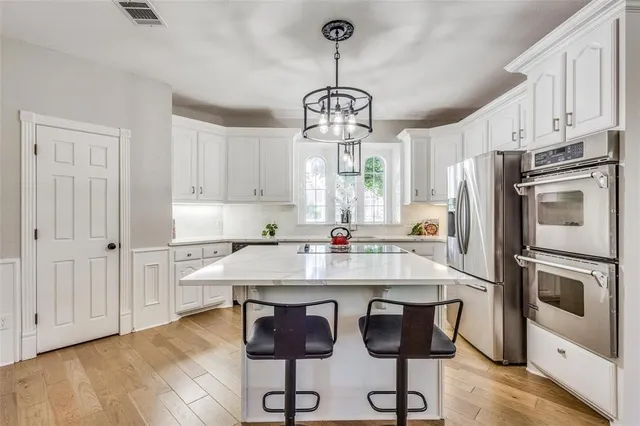 a kitchen with stainless steel appliances a kitchen island hardwood floor sink and window
