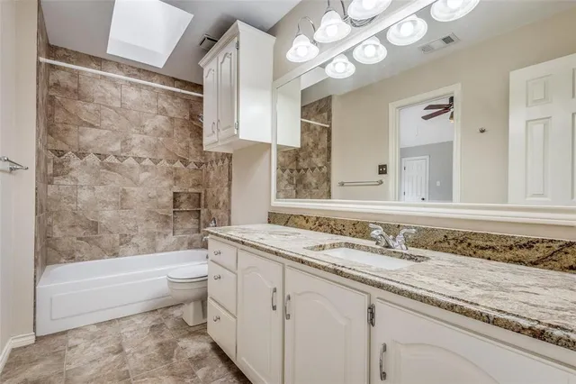 a bathroom with a granite countertop sink a toilet and bathtub