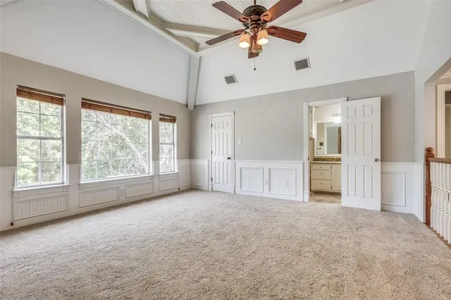 an empty room with chandelier fan and windows