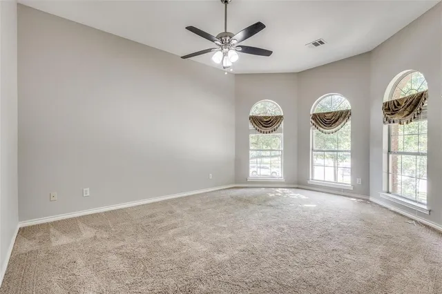 an empty room with a window and a fan