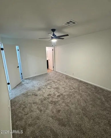 an empty room with a ceiling fan and window