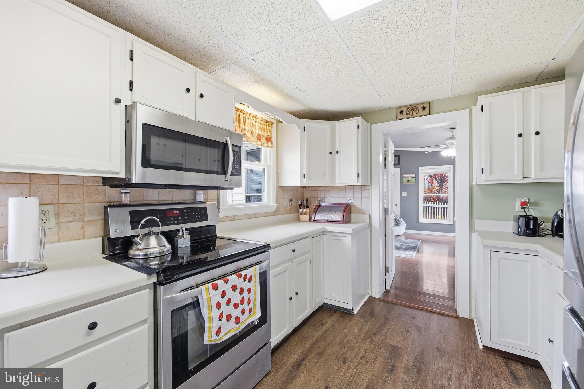 24295 Senedo Road Woodstock, VA 22664 - Photo 14 of 43 a kitchen with stainless steel appliances a stove a sink a refrigerator white cabinets and wooden floor