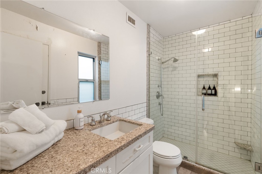 1447 North Kings Road West Hollywood, CA 90069 - Photo 26 of 40 a bathroom with a granite countertop sink a toilet and a mirror