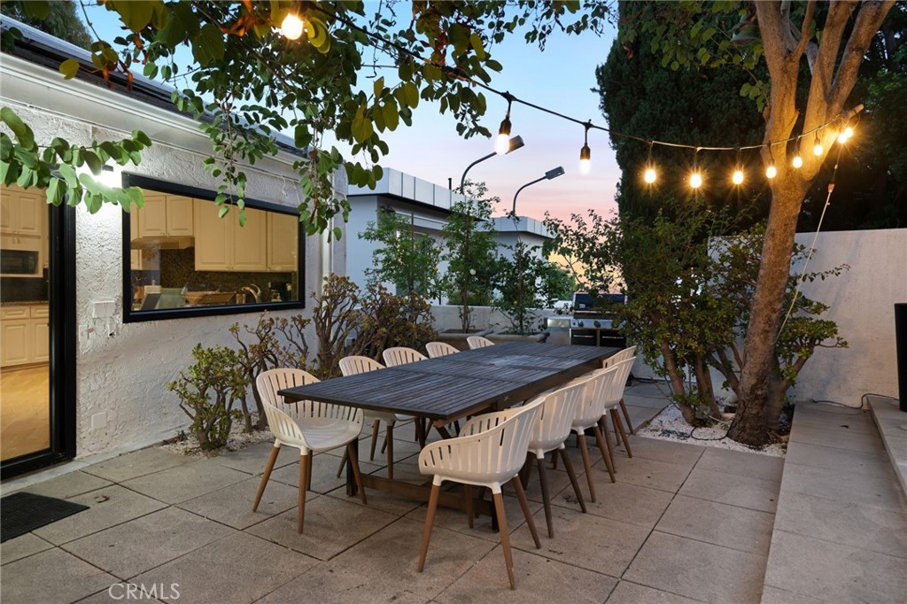 1447 North Kings Road West Hollywood, CA 90069 - Photo 38 of 40 a view of a patio with table and chairs with potted plants and a large tree