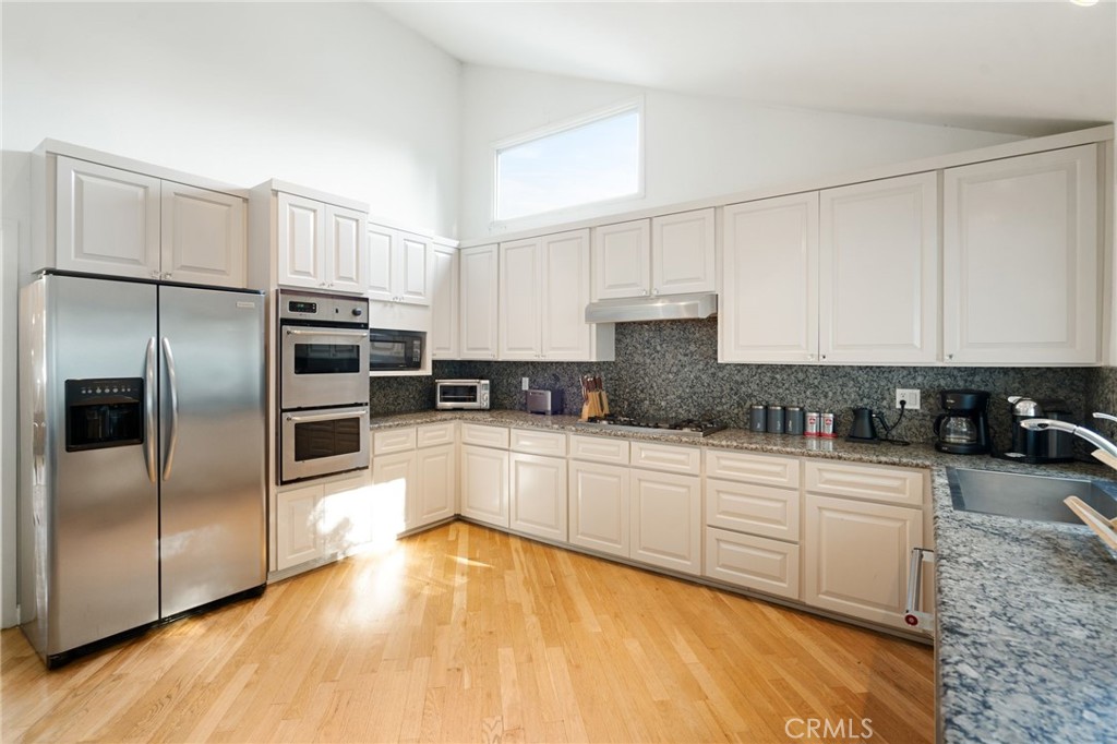 1447 North Kings Road West Hollywood, CA 90069 - Photo 9 of 40 a kitchen with stainless steel appliances granite countertop a refrigerator sink and white cabinets
