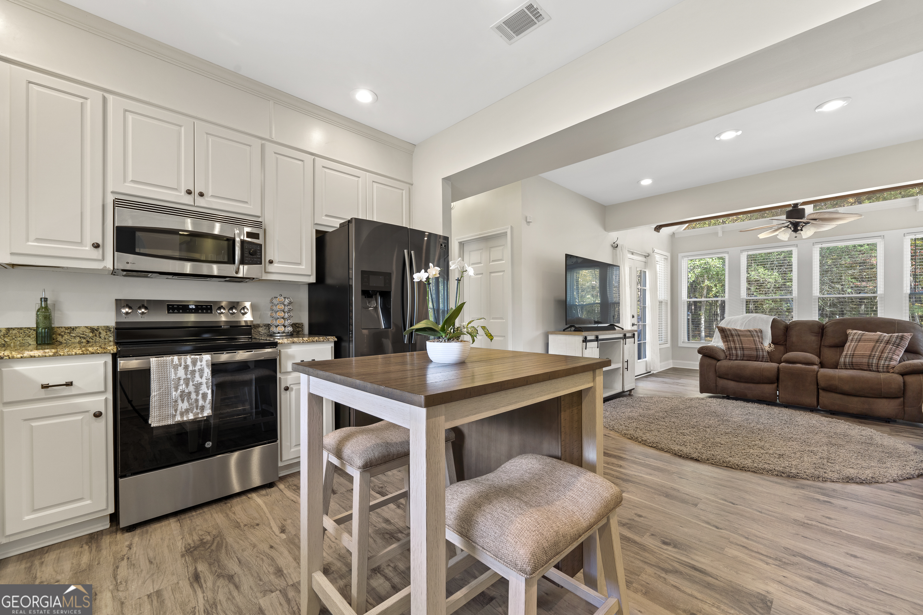 1050 Sugar Creek Church Road Madison, GA 30650 - Photo 14 of 60 a kitchen with stainless steel appliances a stove a sink dishwasher a refrigerator and a dining table with wooden floor