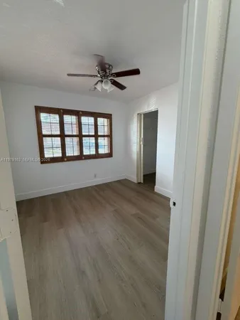 a view of empty room with wooden floor and fan
