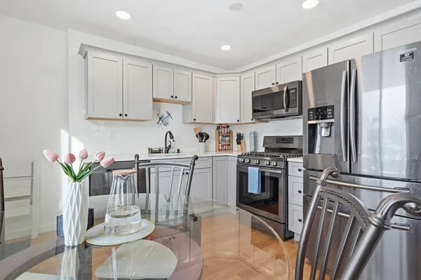 a kitchen with stainless steel appliances granite countertop a refrigerator a stove top oven a sink dishwasher and white cabinets with wooden floor