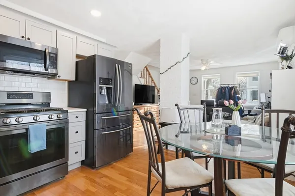 a kitchen with stainless steel appliances a table chairs microwave and refrigerator