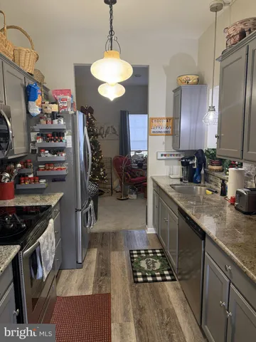 a kitchen with stainless steel appliances a stove a sink dishwasher and a refrigerator with wooden floor