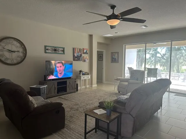 a living room with furniture a flat screen tv and a large window
