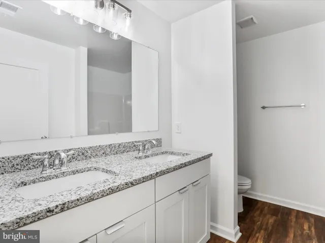 a bathroom with a granite countertop sink and a toilet