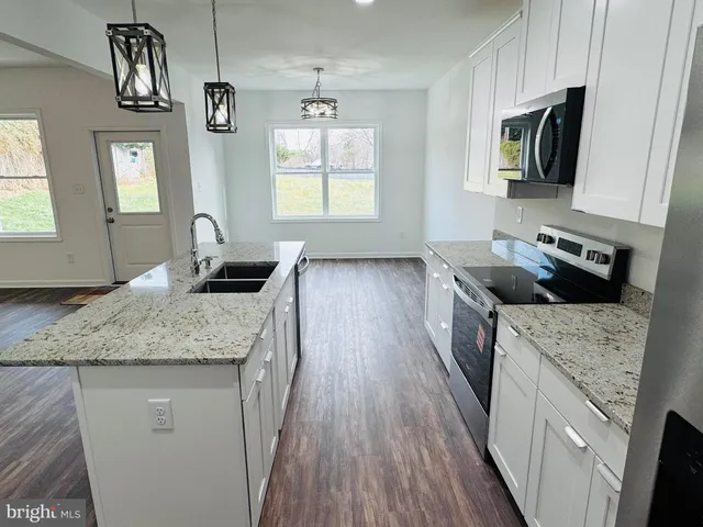 a kitchen with granite countertop a sink a counter space appliances and cabinets